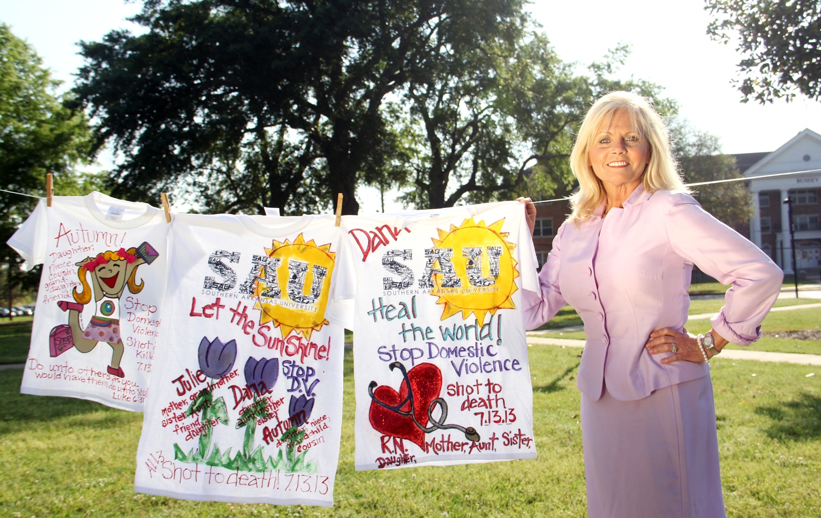 Ceil Bridges, director of alumni relations, stands with three shirts she designed in honor of Julie Hartsfield and her daughter and granddaughter, Dana and Autumn. The shirts were part of the Clothesline Project, a traveling exhibit that raises awareness for domestic abuse. The exhibit was recently on display on the SAU Mall as part of Domestic Violence Awareness month.