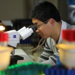 Xi Wu with a microscope Xi Wu looks through a microscope in a science lab
